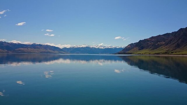 Aerial drone footage close to reflective water of Lake Hawea flying pan
