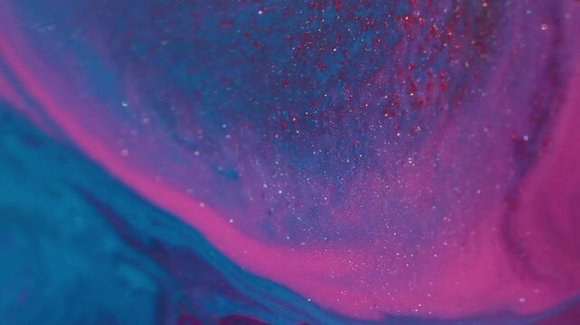 Bokeh spreading particles. Glitter mix. Defocused pink purple blue color ink in water acrylic wet spilling on abstract bokeh background.