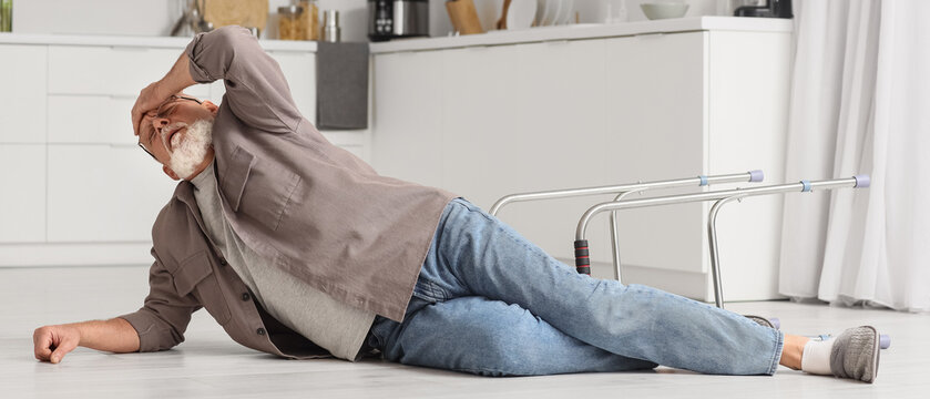 Senior man lying on floor after fall with walker in kitchen