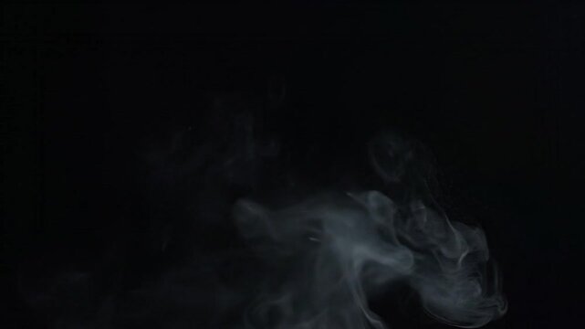 Wisps of ethereal mist rise against a deep black void