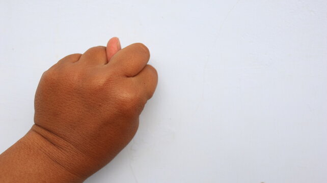 Person hand making a gesture against a plain white backdrop with ample copy space