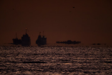 夜明けの明け始めた水平線の船と島影20251122