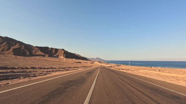 Car driving on coastal desert highway with mountains and seaview