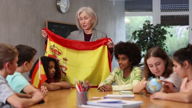 children listen with interest to the teacher, who talks about the geographical location Spain