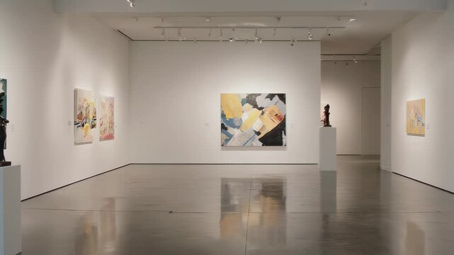 Modern art gallery with paintings and sculptures displayed on white walls and pedestals