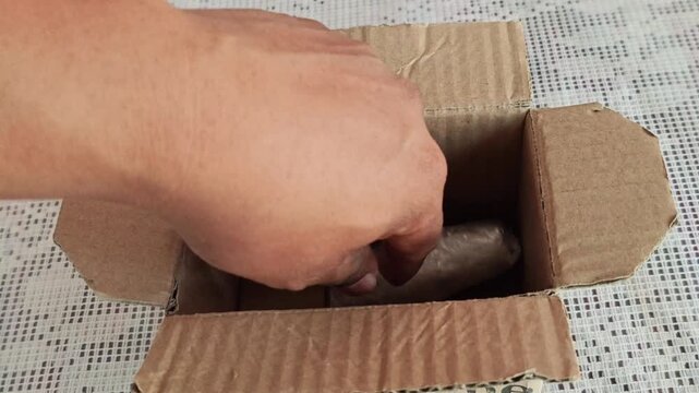 Hands packaging a bottle of distilled turpentine oil for shipping.