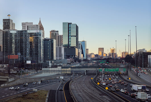 View of the Downtown Atlanta Skyline Cityscape showing several prominent buildings, highways, cars, and hotels after sunrise.