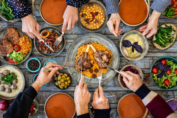 Iftar, break the fasting at holy Ramadan with family, top view of a dining table at iftar time when many human hands sharing their meal. 