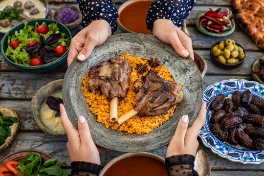 Iftar, break the fasting at holy Ramadan with family, top view of a dining table at iftar time when many human hands sharing their meal. 