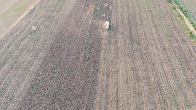 Ginosa, Italy. Harvesting a field with a combine harvester in the light of the evening sun. Drone footage, Departure of the camera, Departure of the camera