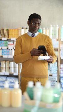  Adult man buyer scanning qr code for box of ointment in pharmacy 