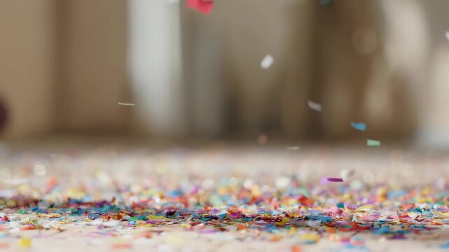 Colorful confetti scattered on a light-colored surface, falling from above
