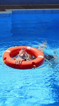 Water rescue practice, role-playing emergency water rescue in pool, and simulating rescue using life preserver under supervision of instructor. Training session rescue procedures using life preserver