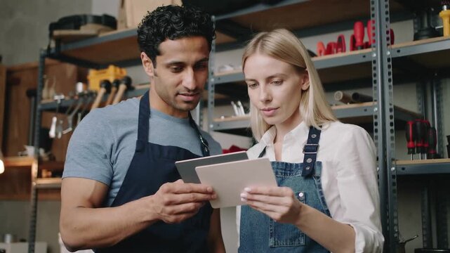 Two Craftspeople Reviewing Plans in Workshop with Tools