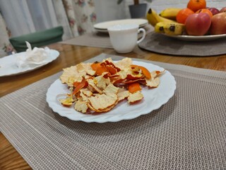 Tangerine peel on white plate after eating. Healthy food concept with fruit leftovers for meal ending. Home dining scene.