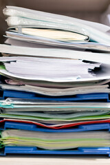 A stack of colorful files and documents on a shelf in an office