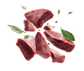 Juicy pieces of beef meat and seasonings float on a white background