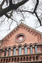 Historic church tower with red brick and cross on top.