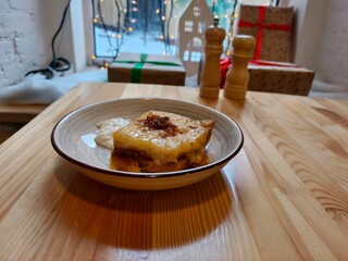 Potato casserole with cheese and sauce in a bowl on a wooden table. Delicious comfort food for home cooking recipe.