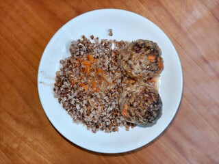 Hearty meatballs with buckwheat and vegetable sauce. Traditional homemade meal on a white plate for healthy eating and simple dinner concept.