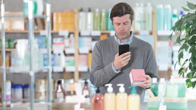 Man in pharmacy scans QR code on antiallergic pills box product, studies product in detail, collects information online. Client learns information about product, reviews and recommendations for use