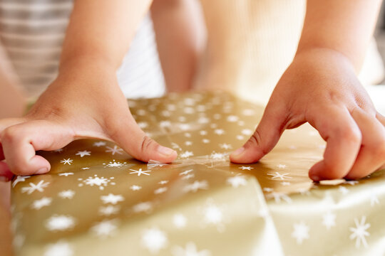 Child hands putting sticky tapes on wrapping paper
