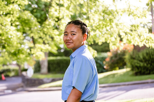 Teenage Samoan girl looking back while standing on the roadside under the tree