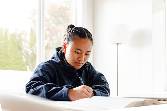 Teenage Samoan girl doing her homework on the table