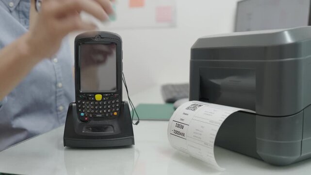 Woman uses a laptop or notebook to print bar code stickers on a bar code printer. Selective focus at sticker barcode.