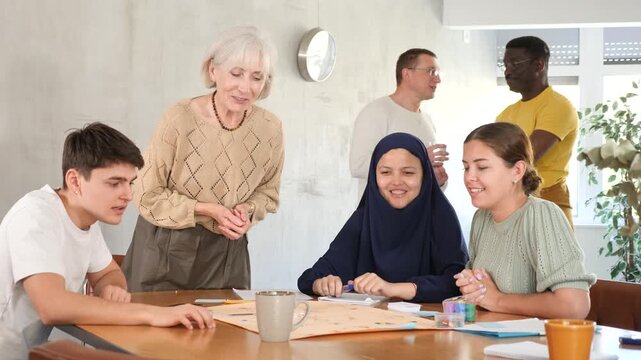 Group of multinational students of different years play a board game with passion 