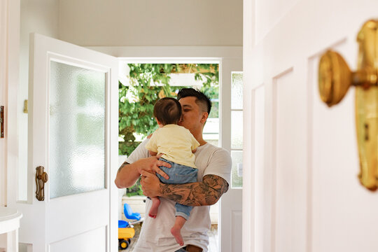 Asian father standing in the doorway holding baby girl