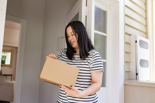 Asian woman holding a package left at the doorstep