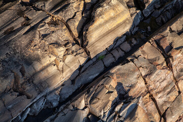 The texture of a stone cliff illuminated by the setting sun