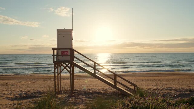 Water rescue cabin on high wooden ground on sunset ocean beach. Lifeguard station controls situation on tranquil sea coast. Small building for guard at seaside. Summer landscape