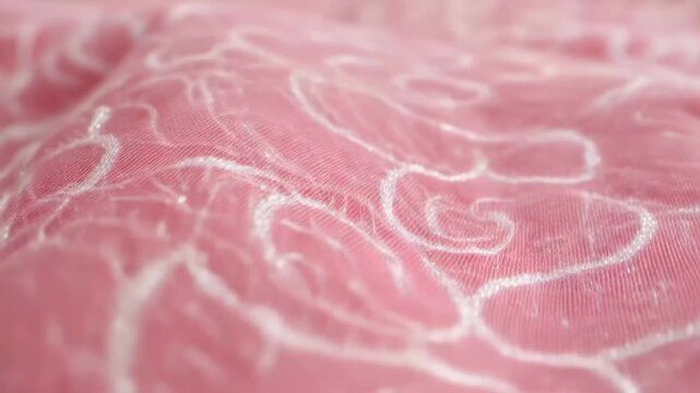 Close look at pink fabric with white design showing fine details of texture and pattern during daylight hours
