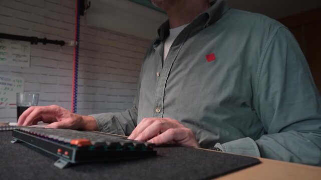 Senior adult programmer coding on a mechanical keyboard at night