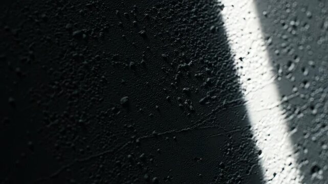 Close-up of a rough textured grey surface with small bumps and shadows from side lighting