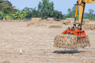 Excavator Handling Biomass Bales in Harvested Agricultural Field