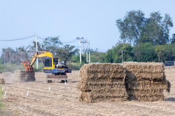 Excavator Handling Biomass Bales in Harvested Agricultural Field