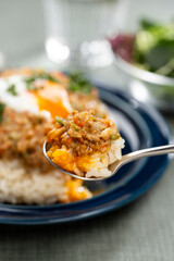 スプーンで掬い半熟卵をのせたキーマカレーを食卓でたべる