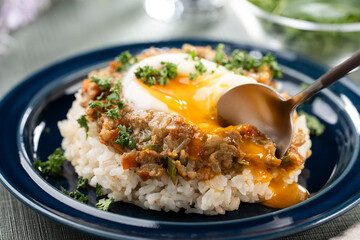 食卓で半熟卵が絡むキーマカレーをスプーンで掬ってたべる