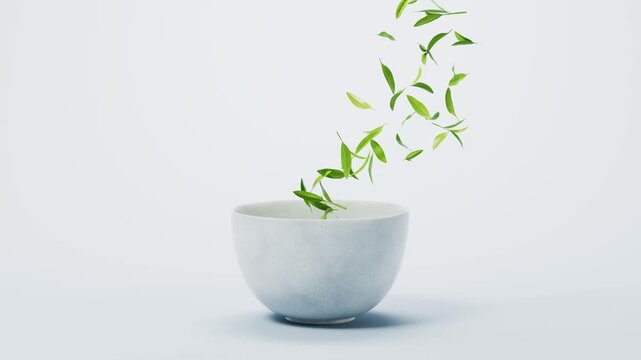 Green tea leaves dance and fall into white bowl in studio lighting