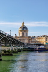 Fototapeta premium riverside view of Institut de France in Paris, historic domed architecture reflected in calm Seine waters, Pont des Arts visible