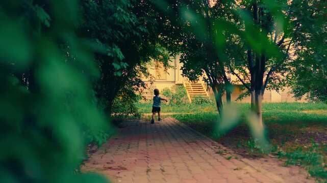Father chasing laughing little son while playing on summer park path