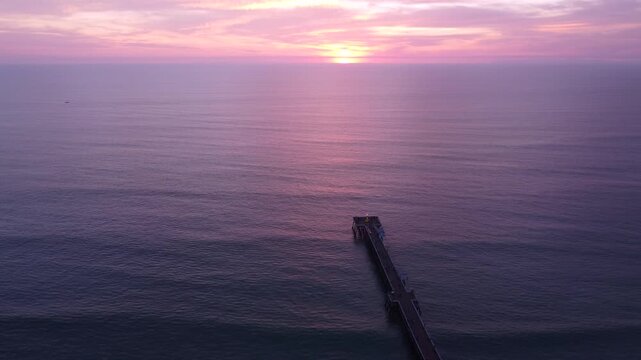 Pink Sunset above the San Clemente Pier in Southern California. Seasonal festive holiday decorations outdoors in public. Overlooking the Horizon. Christmas Tree with a Star on top at the end.
