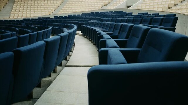 Empty modern auditorium with comfortable blue seats and wide aisle in a large venue for events and presentations