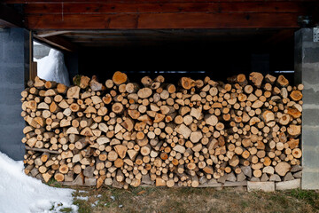 Stacks of firewood near the house. Preparing firewood for winter, chopped bundles, warmth in the fireplace