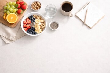 Fototapeta premium Healthy breakfast flat lay with granola bowl, fresh berries, banana, nuts, coffee, water and notebook on light background. Clean nutritious morning food concept with copy space. 