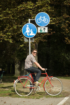 Young man in his twenties cycling on urban bike path in green park
