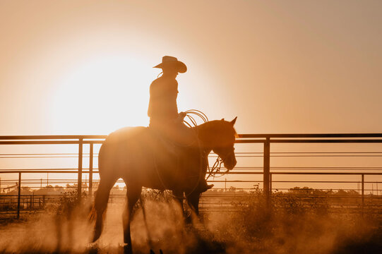 Cowboy riding his horse in the dusty area at sunset